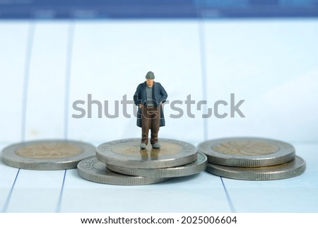 Miniature people toy figure photography. Bankruptcy concepts. A sad man with no money standing on coin stack above bank account saving book. Isolated on white background. Image photo