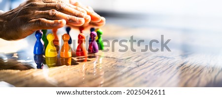 Inclusion, Diversity And Equality. African Hands Safeguard Wooden pawns Royalty-Free Stock Photo #2025042611