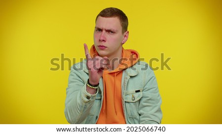 I am warning you! Student boy shakes finger and saying no, be careful, scolding and giving advice to avoid danger mistake, disapproval sign. Young man studio shot isolated on yellow wall background