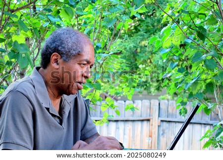 African american male working on his laptop computer outside on patio deck.