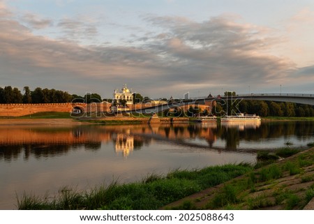 View of the Sofia Embankment, the Novgorod Kremlin and the Humpback Bridge from the opposite bank of the Volkhov River on an early cloudy summer morning, Veliky Novgorod, Novgorod Region, Russia Royalty-Free Stock Photo #2025088643