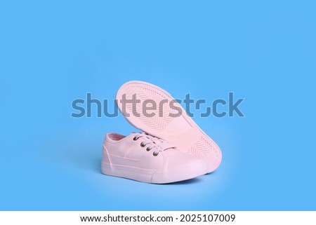 Pair of comfortable sports shoes on turquoise background