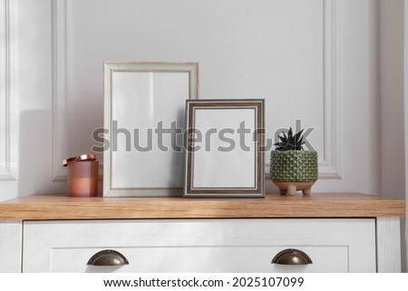 Empty photo frames and succulent on chest of drawers indoors