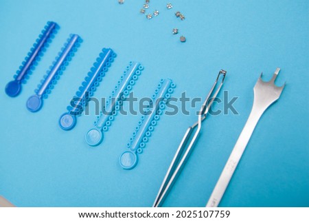 Braces elastics and dental instruments on blue background