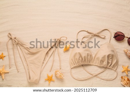 Stylish bikini, sunglasses, starfishes and shells on sand, flat lay. Space for text