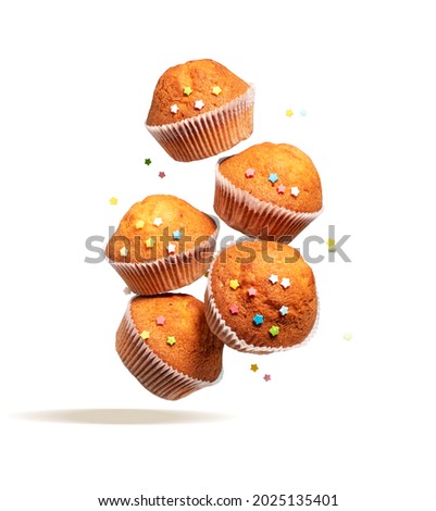Fly delicious vanilla cupcakes. Cupcakes in paper liners with colorful icing stars fly isolated on white background.