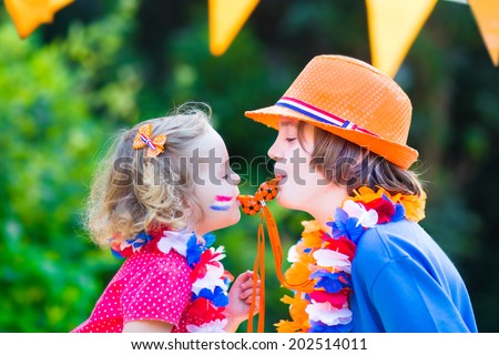 Two Dutch children, teenager boy and funny little girl, fans and supporters of Dutch football team, celebration championship victory playing with whistles decorated with flags 