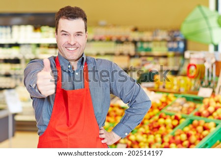 Happy salesman congratulates with his thumbs up in a supermarket