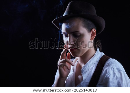 serious young woman smoking cigarette on black background,