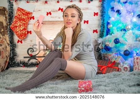 christmas concept - young woman taking selfie photo near fireplace decorated christmas tree