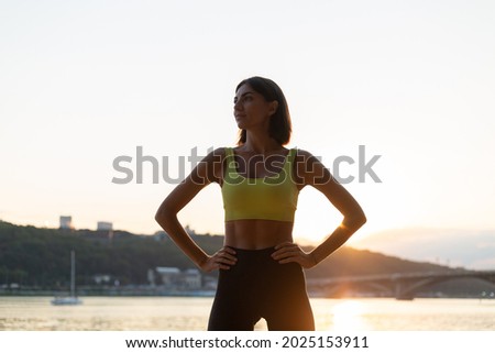 Good looking in perfect shape slender woman in sport wear at sunset on city beach with strong abs core