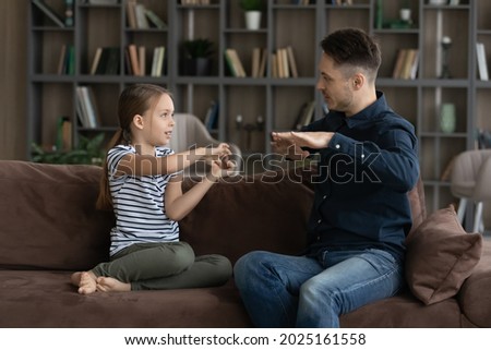 Little 7s deaf girl her father sit on couch speaking without words showing visual manual gestures using symbols. Professional speech therapist teach child. hearing impairment, communication concept Royalty-Free Stock Photo #2025161558
