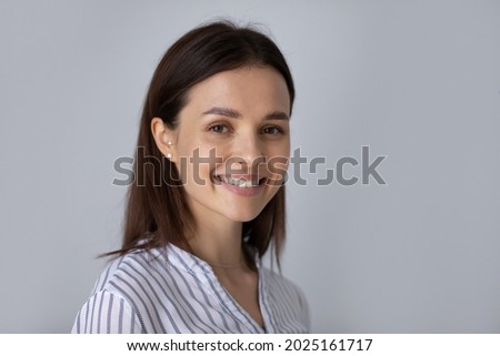 Portrait of smiling young Caucasian woman isolated on grey studio background look at camera posing. Profile picture of happy beautiful 20s European female feel excited. Leadership, diversity concept.