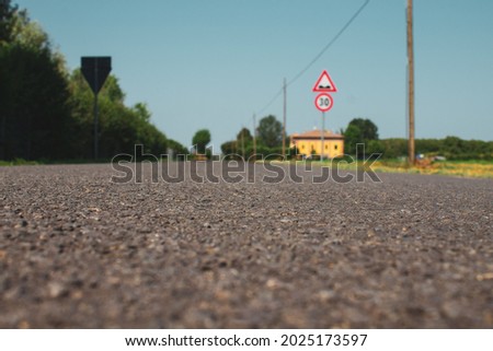 Low angle view on an asphalt road. Road signs and trees on the background. Selective focus. Copy space.