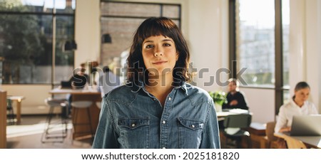 Portrait of freelancer standing in co-working space. Confident businesswoman looking at camera.