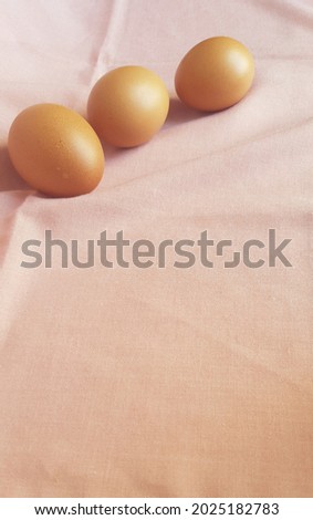 This is a photo of three eggs laid on a pink cloth.