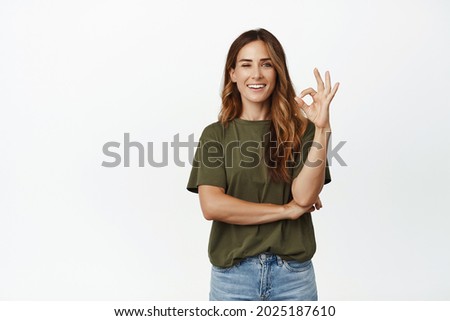 Yes, very good. Smiling pleased adult woman nod, show OK okay sign in approval, agree with you, like and recommend product or company, praise quality white background