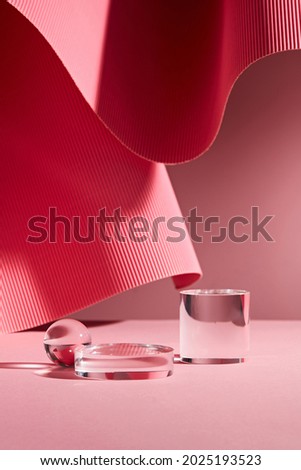 Abstract background for branding and minimal presentation. Glass podium on folding paper pleated geometric pink background. 