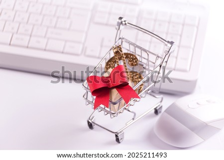 Online shopping and e-commerce concept photo with a shopping trolley full of paper cut gift boxes against the white keyboard.