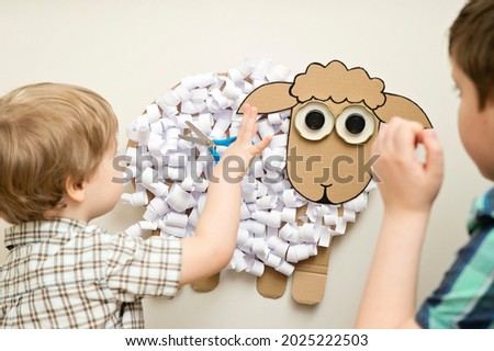 The boy cuts a paper sheep. DIY toy. Activity at home. Early education, fine motor skills. Montessori methodology.