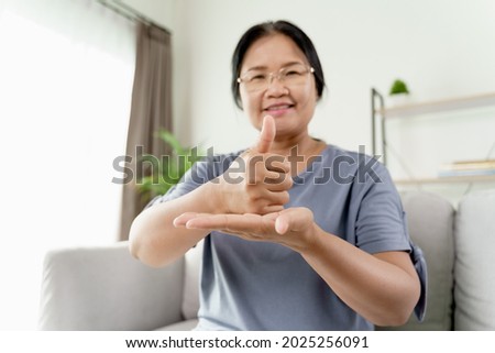 Mature Asian deaf disabled woman using Sign Language to communicate with other people.