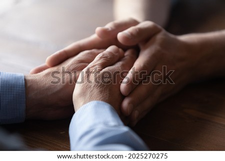 Crop close up of old Caucasian father and adult son hold hands show family unity and support. Supportive mature dad and grownup child demonstrate love care, comfort and caress. Bonding concept. Royalty-Free Stock Photo #2025270275