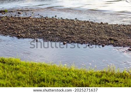 selective focus on small stones At the water's edge, there is a small green grass, the picture of nature gives a feeling of freshness, the view is low. There is space for text. nature wallpaper