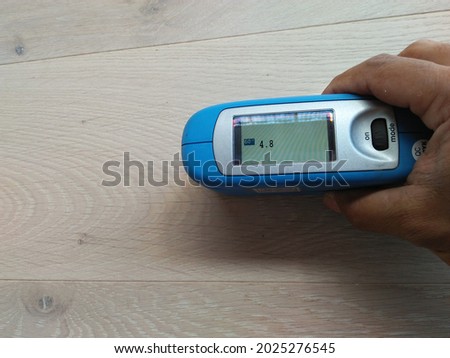 Measuring the gloss of a paint film by gloss meter on the wood

