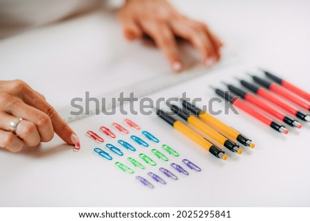 Woman with OCD – Obsessive compulsive disorder concept. Placing paperclips in a straight line. Royalty-Free Stock Photo #2025295841