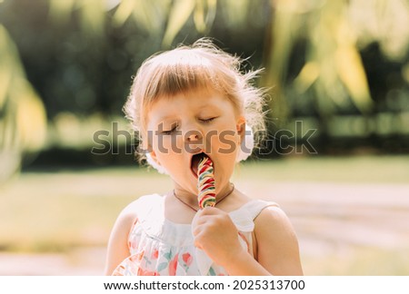 Little cute funny girl licking lollipop
