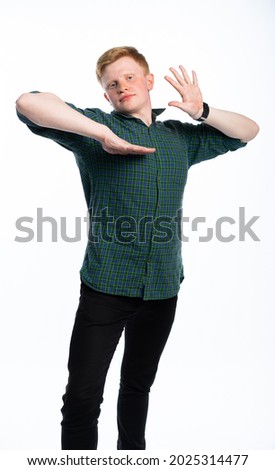 portrait of a red-haired guy in a blue t-shirt and jeans on a white isolated background. teenager dances, scares, or pretends to be someone