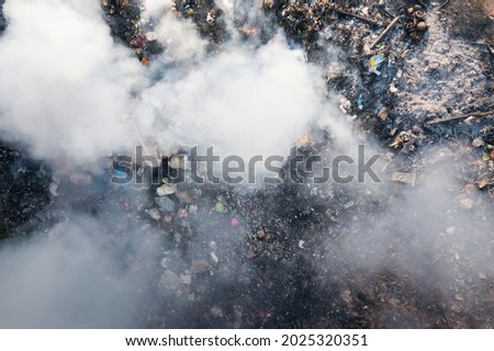 Garbage and fire burn in landfill. Also call trash, waste, rubbish. Destruction with combustion, heat, flame. Occurs smoke, toxic cause of air pollution, environmental damage and global warming. Royalty-Free Stock Photo #2025320351