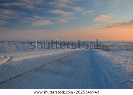 In front of us is a road that goes into the distance at dawn in the middle of a snowy desert. The road to Teriberka