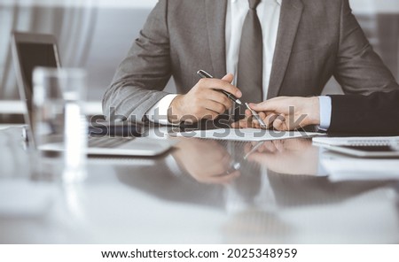 Unknown business people working together at meeting in modern office, close-up. Businessman and woman with colleagues or lawyers discussing contract at negotiation