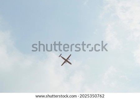 View of the light blue sky where a white plane flies.
