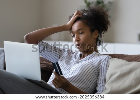 Unhappy millennial African American woman distressed with problems paying online on laptop with credit debit card. Upset young ethnic female confused have troubles shopping on web on computer. Royalty-Free Stock Photo #2025356384