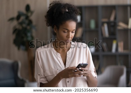 Young African American woman use smartphone text message online on modern gadget. Millennial mixed race female speak talk on video webcam call on cellphone device. Technology, communication concept. Royalty-Free Stock Photo #2025356690