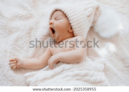 cute yawning newborn baby in a white knitted hat . Royalty-Free Stock Photo #2025358955