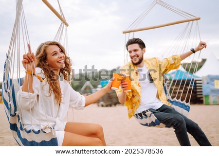 Young and cheerful couple at a music festival. People drinking beer and having fun. Youth, party, vacation concept. Royalty-Free Stock Photo #2025378536
