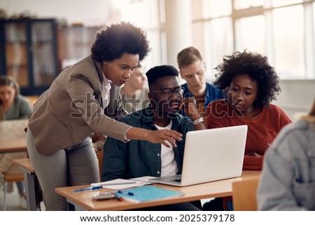 African American professor and her students using laptop during lecture in the classroom. Royalty-Free Stock Photo #2025379178
