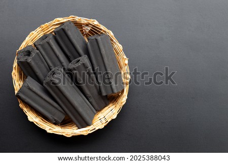 Non smoke wood charcoal in bamboo basket on dark background.