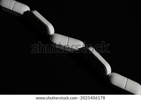  white oval pills lying in a row on a dark background 