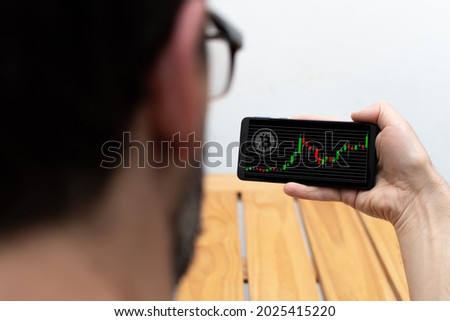 Person consulting cryptocurrency charts from a smartphone