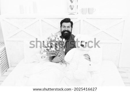 Happy moments. good morning surprise. happiness about present. cheerful bearded man in bed. happy birthday gift. spring fresh tulip and bear toy. love valentines day. womens day. flowers for march 8