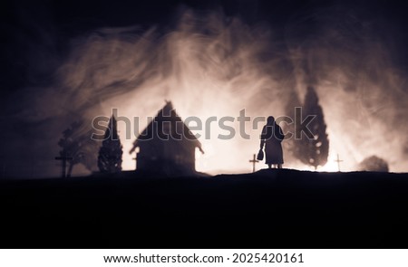 Silhouette of old woman with a cane walking at cemetery at night. Horror Halloween concept. Artwork decoration with light and fog. Selective focus