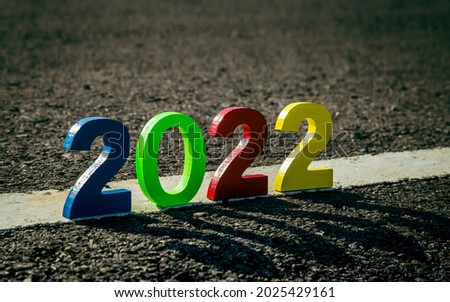 Welcome year 2022. Sunlight and shadow of numbers 2022 on the black asphalt of road, background, close-up