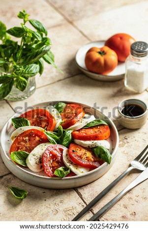Plate of Caprese Salad with Mozzarella Cheese, Tomatoes and Basil Royalty-Free Stock Photo #2025429476