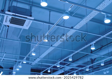 Ceiling with bright lights in a modern warehouse, shopping center building, office or other commercial real estate object. Directional LED lights on rails under the ceiling Royalty-Free Stock Photo #2025429782