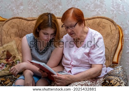 The grandmother shows her granddaughter her old photos from the family album. A happy family.