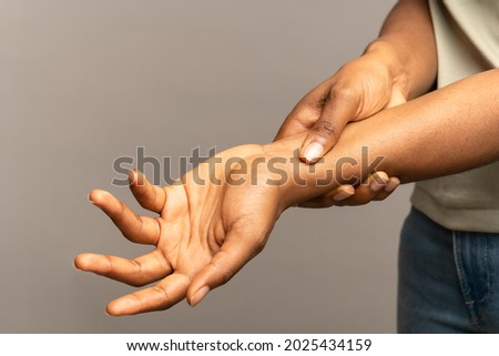 Close up of african woman arms holding painful wrist after work on laptop computer, suffering from weakness and tingling, carpal tunnel syndrome, arthritis, neurological disease. Numbness of hand